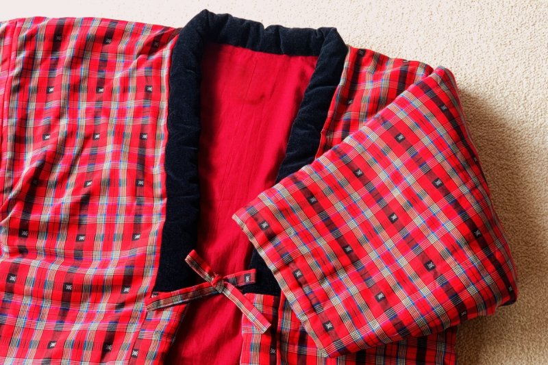 A red plaid hanten with a black collar and soft padded cotton, showing its traditional structure.
