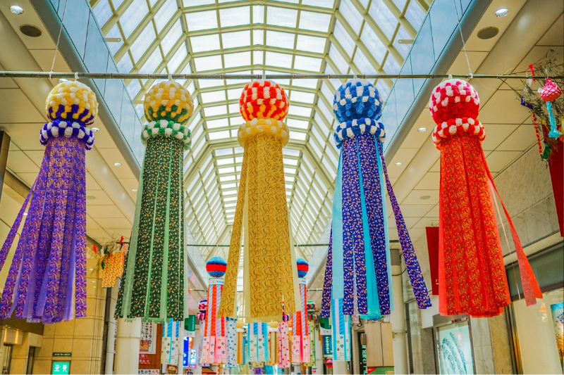 Large Tanabata fukinagashi streamers hanging in a shopping arcade, creating a lively festival atmosphere.