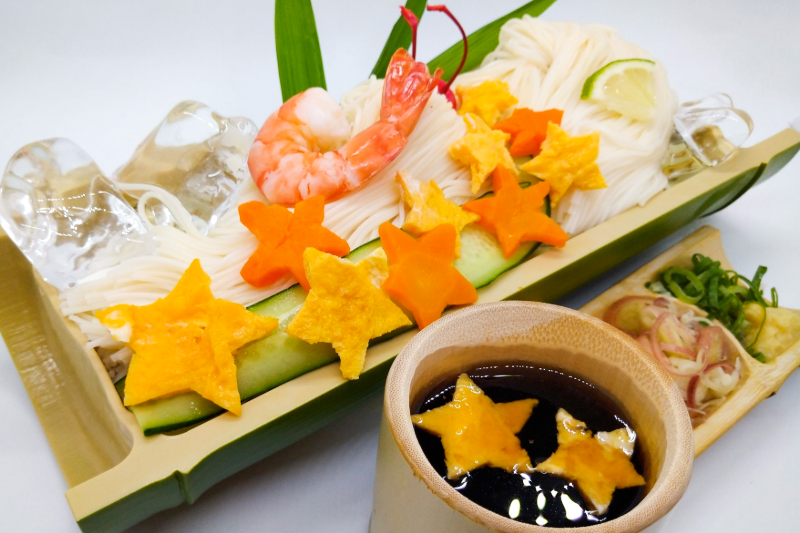Chilled somen noodles served with star‑shaped vegetables, shrimp, and dipping sauce in a bamboo tray.