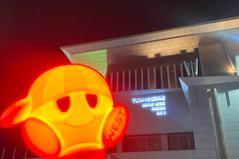 A red penlight held in front of Marine Messe Fukuoka Hall A after a WEST. concert
